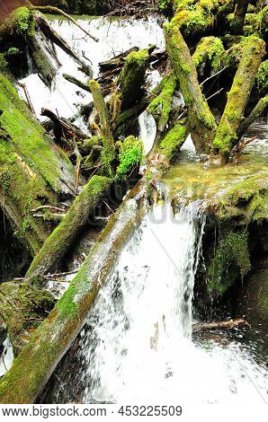 A Stormy River Flows Down The Mountain In A Cascade Of Waterfalls, Skirting Stone Boulders And Falle