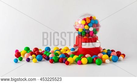 A Plastic Toy Gum Ball Machine Filled And Surrounded By Gum Balls.