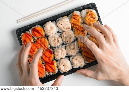 Close-up Of Hungry Hands Reaching For Hot Baked Yaki Maki Rolls. Japanese Traditional Sea Food Cuisi