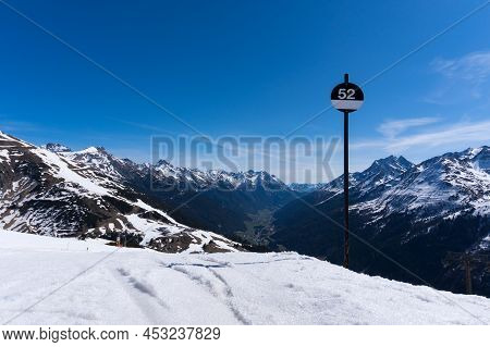 Landscape Shot In Saint Anton At Arlberg In Austrian Alps With Snow And A Black Piste Sign Showing T