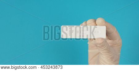 A Hand Hold Atk ( Antigen Test Kit) And Wear Medical Glove On Blue Background.