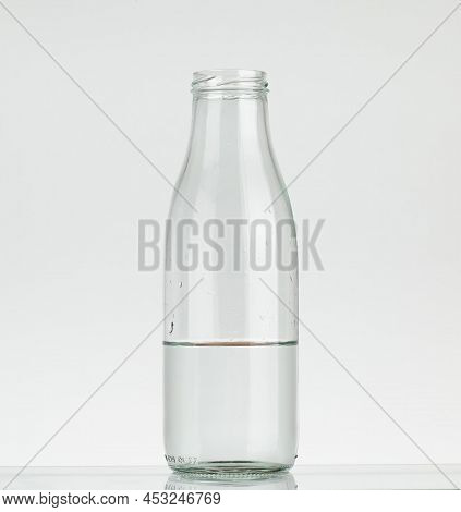 Glass Bottle Half Filled With Water. Water Bottle Without Cap Isolated On White Background.