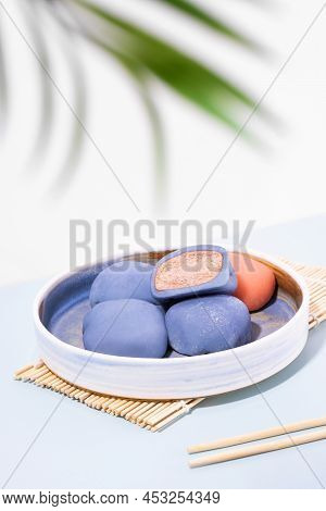 A Plate Of Japanese Mochi With Chopsticks And Wooden Mat On A White Background. Concept Of A Traditi