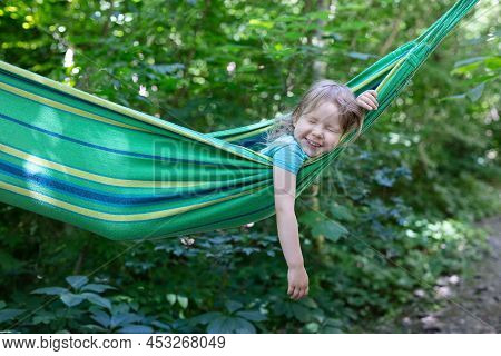 Cute Caucasian Little Girl Laughing While Lying In Hammock