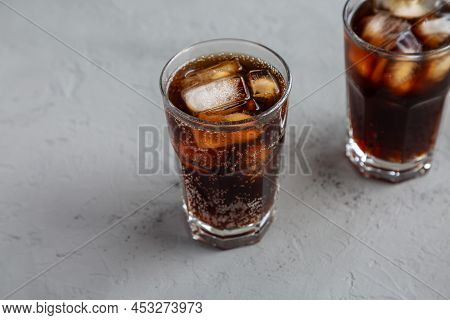 Cold Refreshing Dark Cola With Ice Cubes On A Gray Background, Side View.