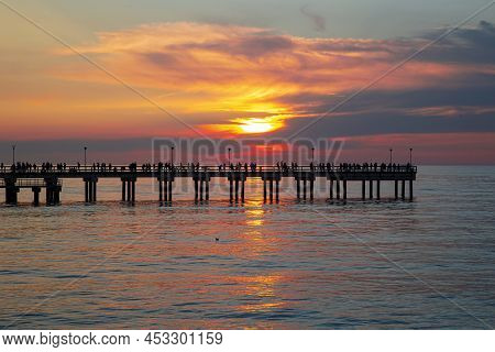 Palanga Pier With People Resting Against The Background Of The Sea Sunset