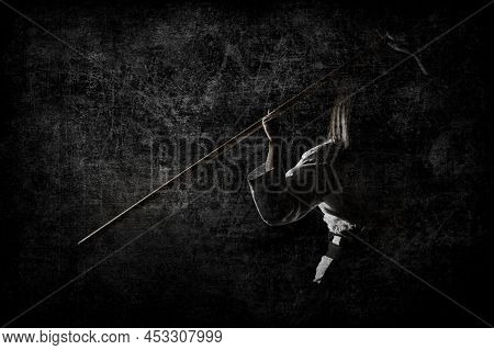 A Girl In Black Hakama Standing In Fighting Pose With Wooden Sword Bokken Over Dark Grunge Backgroun