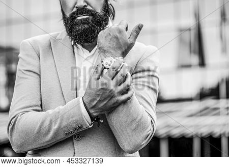 Watch In A Man. Businessman Points To His Watch On The Background Of The Town. Man Holds His Watch. 