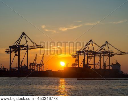 Beautiful Sunset Above Port On Sunset Time With Silhouettes Of Cargo Cranes. Industrial Black Sea Po