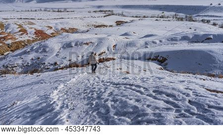 A Path Was Trodden On The Snow-covered Hillside. A Man In A Down Jacket Descends Into The Valley. Br