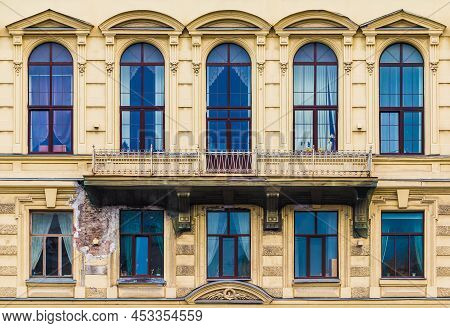 Balcony And Many Windows In A Row On The Facade Of The Urban Historic Apartment Building Front View,