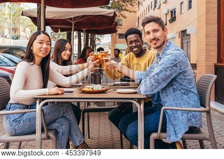 Portrait Of 4 Happy Friends Toasting Seated At A Table On A Terrace
