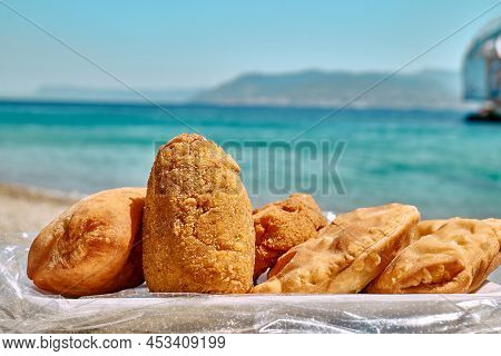 Typical Sicilian Street Food On Seaside Background. Hot Palatable Panzerotti (calzone Pizza Fried In
