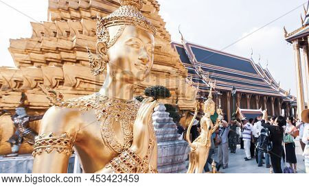 Picturesque Of The Golden Kinnari Statues In The Grand Palace, A Group Of Tourists Blurred In The Ba