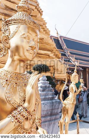 Picturesque Of The Golden Kinnari Statues In The Grand Palace, A Group Of Tourists Blurred In The Ba