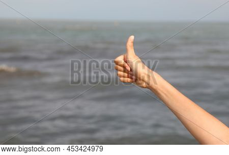 Human Hand Of Young Boy With Thumb Up And Sea On Background