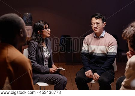 Horizontal Shot Of Young People Gathered In Small Group Siting On Chairs Having Psychotherapy Sessio