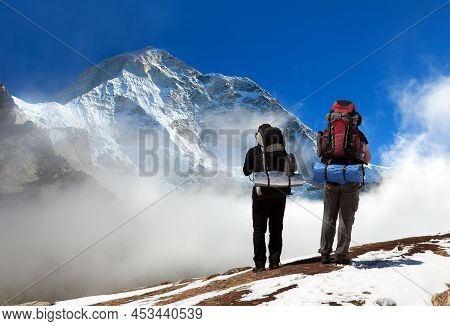 Mount Makalu With Clouds And Silhouette Of Two Hikers, Nepal Himalayas Mountains, Barun Valley