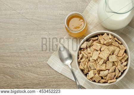 Bowl Of Sweet Crispy Breakfast Cereal, Milk And Honey On Wooden Table, Flat Lay. Space For Text