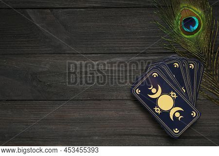 Tarot Cards And Peacock Feather On Black Wooden Table, Flat Lay With Space For Text. Reverse Side