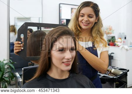 Hairdresser Using Small Mirror To Let Client See Back Of Her Head After Blowdry