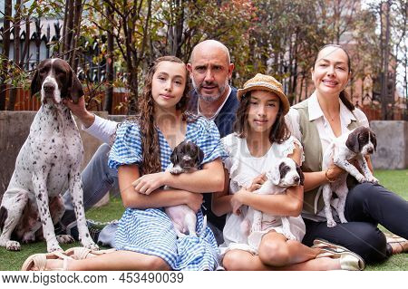 Young family outdoors with their new born puppies in a sunny day