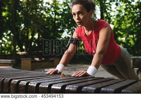 Determined Hispanic Female Athlete Doing Pushups From The Wooden Bench In The City Park, Pumping Her