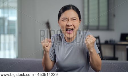 Asian Woman Angry And Shouting Sitting On Sofa At Home.