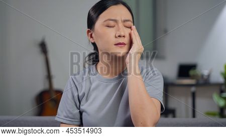 Asian Woman Was Sick With Eyes Pain Sitting On Sofa At Home.