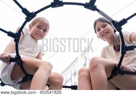 Two Pretty Teen Girls Playing On A Modern Playground In Identical Clothes. Sister, Bffs. Sisterhood,