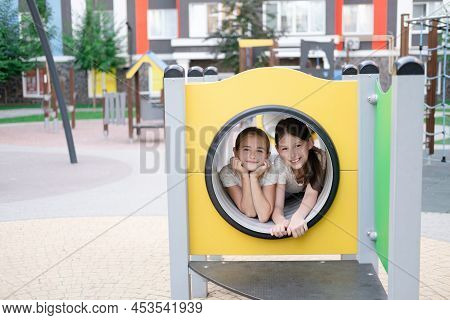 Two Pretty Teen Girls Playing On A Modern Playground In Identical Clothes. Sister, Bffs. Sisterhood,