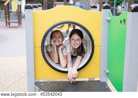 Two Pretty Teen Girls Playing On A Modern Playground In Identical Clothes. Sister, Bffs. Sisterhood,