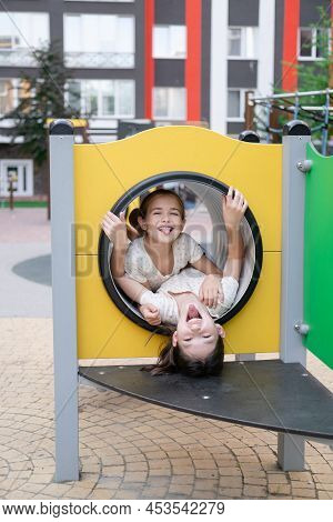 Two Pretty Teen Girls Playing On A Modern Playground In Identical Clothes. Sister, Bffs. Sisterhood,