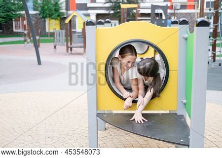 Kids Outdoors Having Fun On Modern Playground With New Colorful Equipment. Sisterhood, Friendship. T