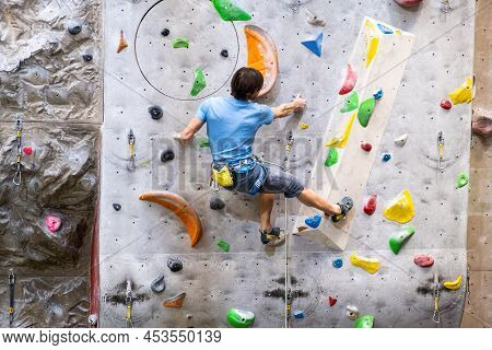 The Climber Trains On The Artificial Rock Wall With Insurance In Bouldering Gym, April 2022, Prague,