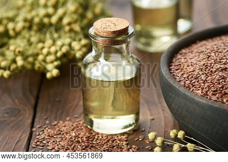 Bottle Of Fresh Linseed Oil And Bowl Of Whole Flax Seeds. Bundle Of Linen Flax Plants On Table.