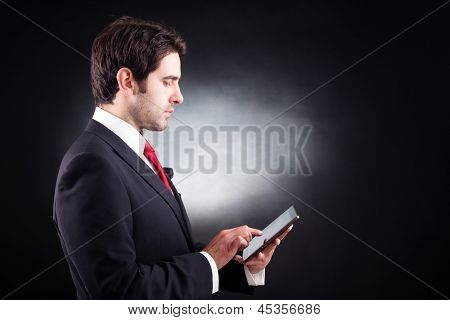 Hombre de negocios guapo con tablet PC sobre fondo negro