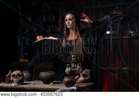 Halloween Concept. Witch Dressed Black Hood With Dreadlocks Standing Dark Dungeon Room Use Magic Boo