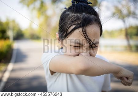 Asian Child Girl Sneezing,coughing Into Her Arm Or Elbow To Prevent Spread Covid-19,coronavirus,avoi