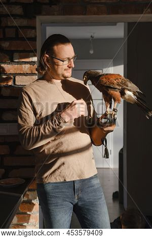 Man Drinking Coffee With Wild Bird At Home On The Kitchen In Morning. Eagle As Pet. Unusual Animals 