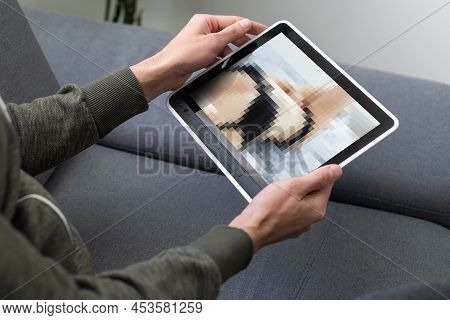 Closeup Of A Young Caucasian Man Watching A Nude Woman In His Tablet Computer