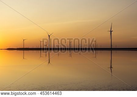 Wind Farm By The Pink Salt Lake Lemuria In Ukraine. Silhouettes At Sunset. Green Energy Concept