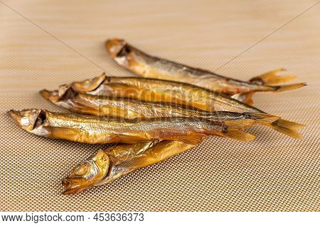 Smoked Capelin Against A Beige Background. Five Ready-to-eat Little Fish. Seafood.