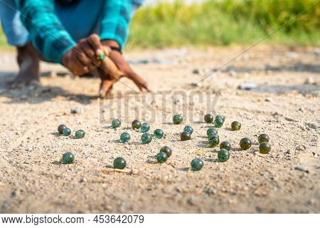 Close Up Shot Of Kid Plyaing By Hitting Goli Or Glass Marbles On Roadside At Indian Village - Concpe