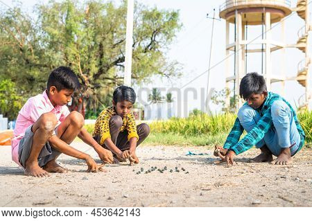 Indian Village Kids Playing Goli Or Marbles On Near Paddy Field - Concept Of Traditional Game, Summe