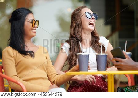 Young Women In Singlasses Joking Around And Laughing When Meeting In Outdoor Cafe On Suturday Aftern