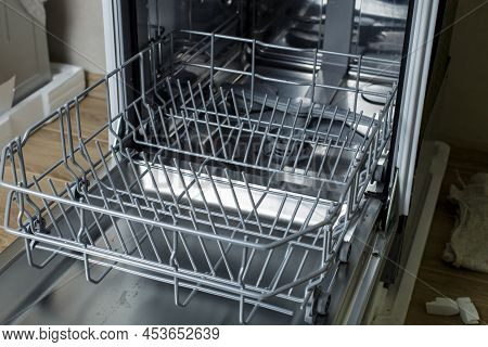 Open Dishwasher. The Hostess Is Preparing To Load Dirty Dishes Into The Dishwasher.
