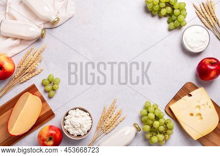 Shavuot Flat Lay Frame With Dairy Products, First Fruits And Wheat On Light Gray Background. Jewish 