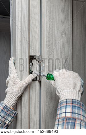Man Screwing A Door Hinge With A Screwdriver. High Quality Photo