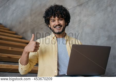 Smiling Indian Man Freelancer Using Laptop Computer Showing Thumb Up Looking At Camera Working Onlin